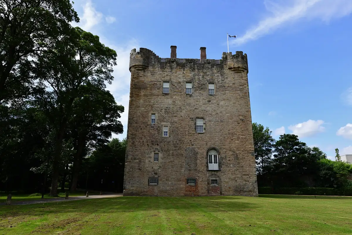 Alloa Tower, the medieval stone keep, standing on a green lawn under blue sky