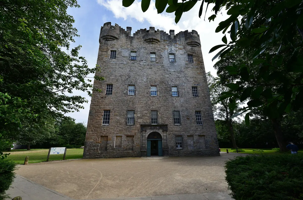 Main entrance and stone facade of Alloa Tower surrounded by trees