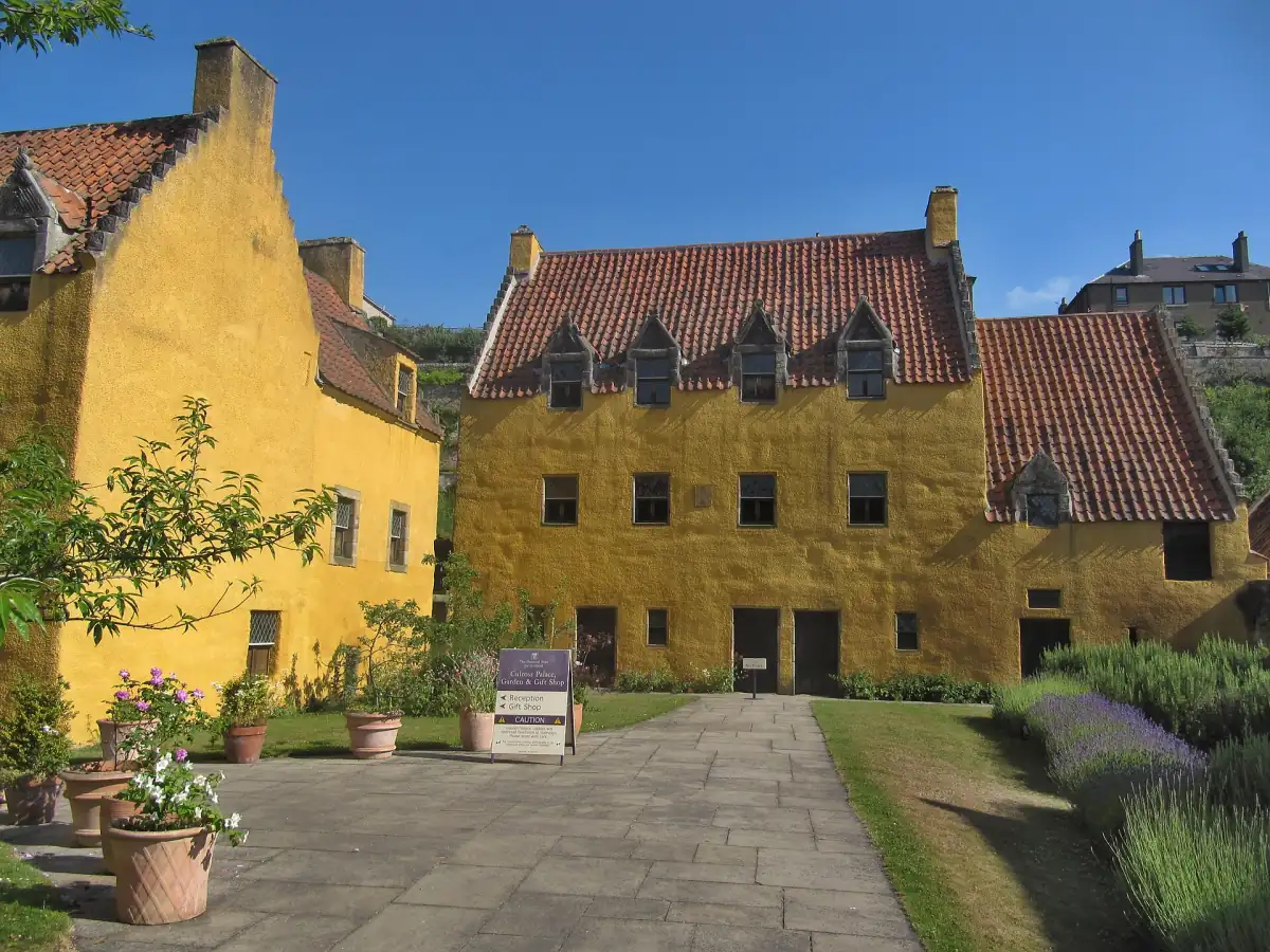 Ochre-coloured Culross Palace with red pantile roofs and a garden path